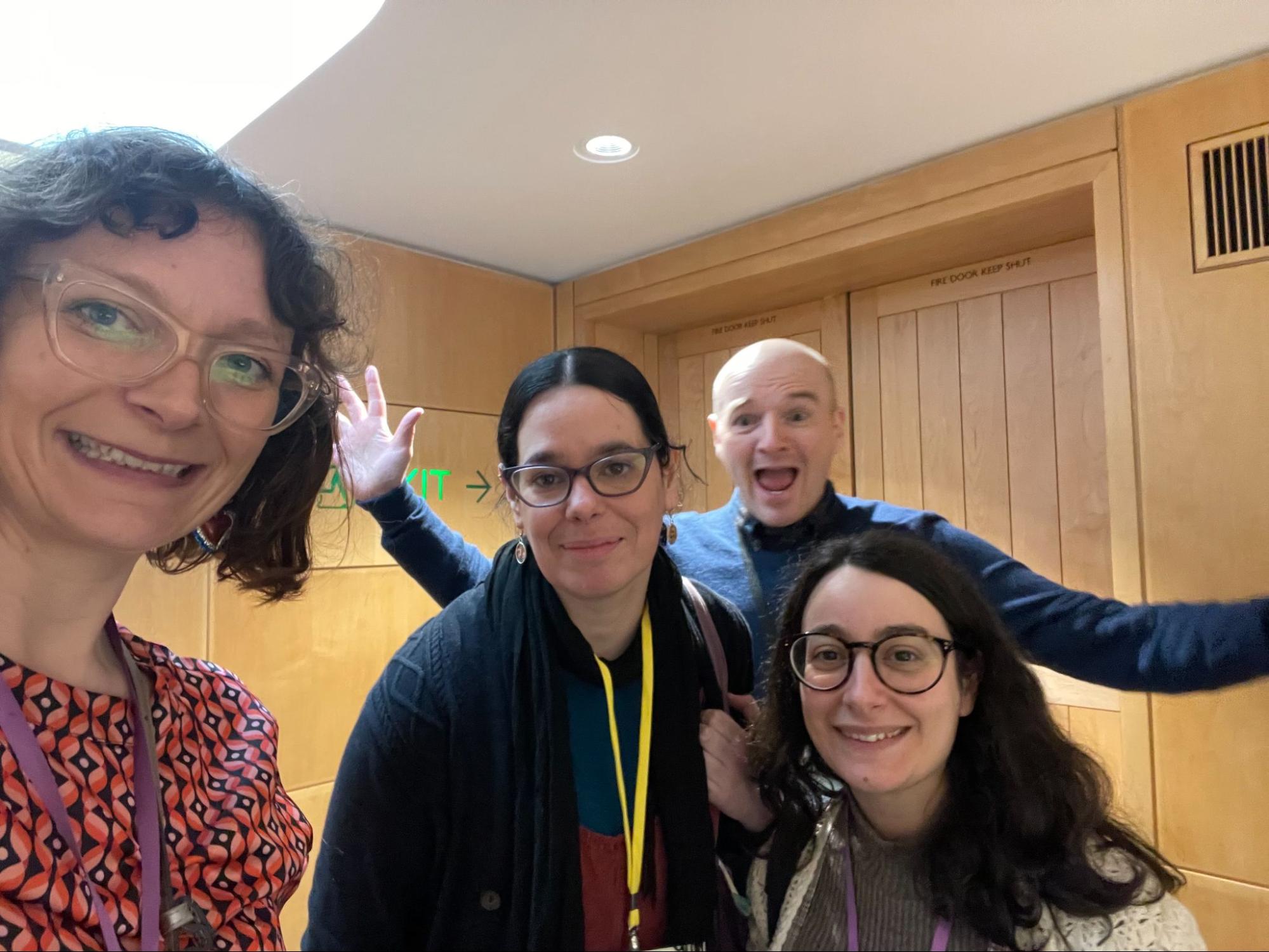 Image Description: This photo shows four people smiling at the camera at the PressPlay event, with one doing “jazz hands” in the background. From left to right: Louise from Good Things, Ana Silva, Luke Oakes and Mari Caruso-Corrado from Cambridgeshire Libraries.